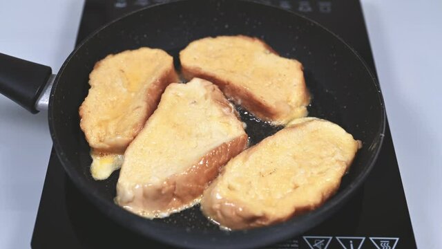 Woman frys in a frying pan and lifts with fork Spanish torrijas or French toasts. Popular dessert for Christmas, Easter or Pascua. 4k resolution