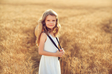 Little girl walking in sunset wheat field