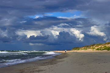Blue dramatic clouds and sunbeams break through over the beach