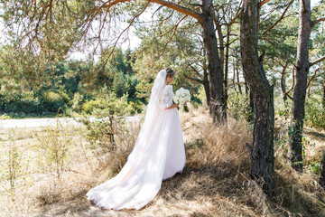Beautiful bride ion wedding dress outdoors in a forest.