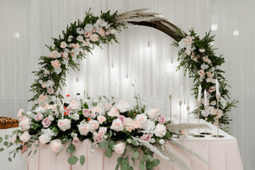 Fototapeta na wymiar beautiful wedding banquet table for newlyweds decorated with wedding decorations. table with food for the bride and groom. a wooden arch is decorated with flowers at the table with food.