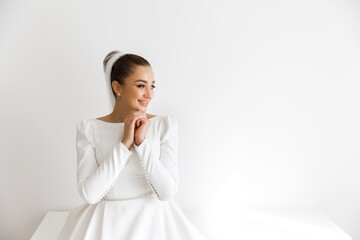 Morning of the bride in a white dress and a veil in the room. Beautiful luxurious bride