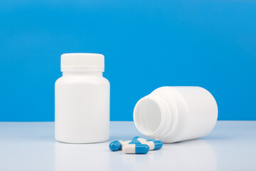 Two bottles with pills against blue background. Close up of medication bottles with spilled pills....