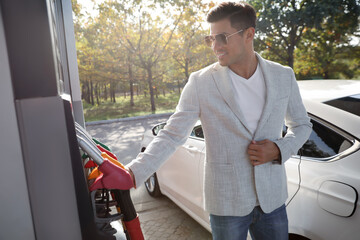 Man taking fuel pump nozzle at self service gas station