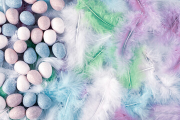 Happy Easter Holiday. Decorative Easter eggs on colorful feathers background. Copy space. Flat lay.