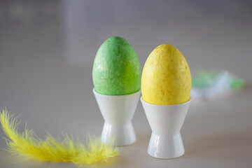 Easter concept. Two decorative eggs in white poached stands and feathers.