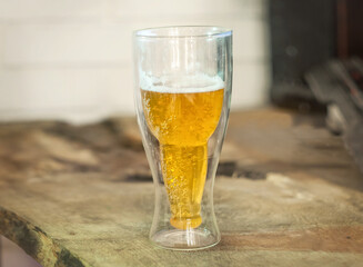 a glass of light beer  with bubbles stands on a wooden table, an old board, a light background