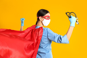 Doctor dressed as superhero posing on yellow background. Concept of medical workers fighting with...