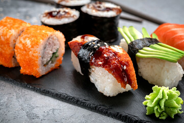 Sushi set of Rolls and nigiri with avocado, salmon and eel on a stone board. Japanese food. Close up