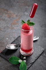 Raspberry mousse with syrup and fresh raspberries on top in glass jars on a stone background. Berry dessert with whipped cream, top view
