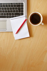 Laptop with coffee cup, notebook and pen on wooden background Top view. Concept for home office. Business concept. Work from home. Desk with laptop, blank notepad, coffee cup and pen on wooden table.