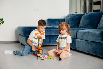 Two young children boy and girl sit on the wooden floor of the house playing educational games