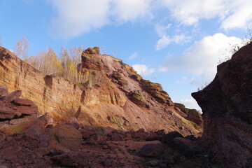 Red hills with birches against a blue sky.