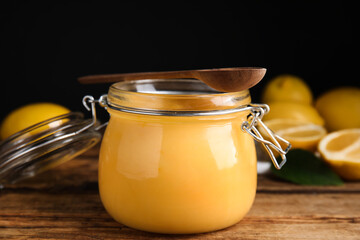 Delicious lemon curd in glass jar on wooden table