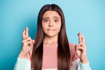 Photo of young preteen girl worried crossed fingers hope show fortune sign isolated over blue color...
