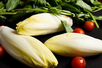 Three endives with basil and several cherry tomatoes