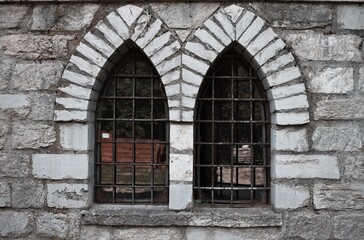 A mullioned window with pointed arches in a medieval stone building (Marche, Italy, Europe)