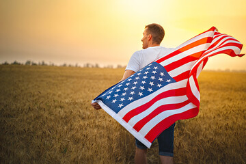 Man holding American flag blowing and waving in farm agricultural wheat field