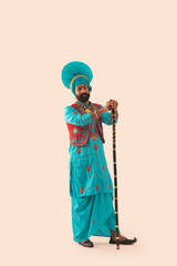 A Bhangra dancer with a grave expression standing with the Khunda.	