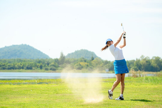 Golfer sport course golf ball fairway. People lifestyle woman playing game golf and hitting out of sand trap go on green grass. Asian female player game shot in summer