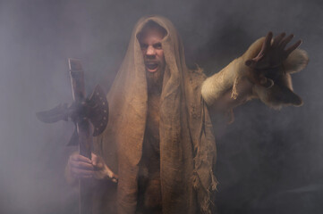 bearded man in a hood with an ancient weapon in his hand