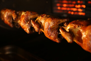 Grilling whole chickens in rotisserie machine, closeup