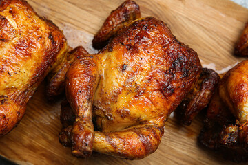 Delicious grilled whole chickens on wooden board, closeup