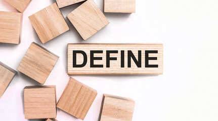 On a light background, wooden cubes and a wooden block with the text DEFINE. View from above