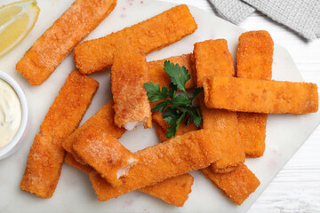 Tasty fresh fish fingers served on white wooden table, flat lay