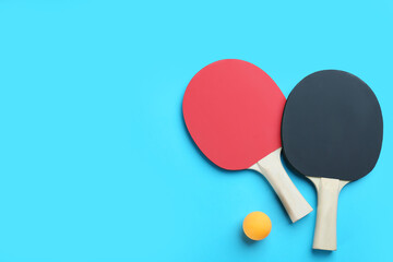 Ping pong rackets and ball on light blue background, flat lay. Space for text