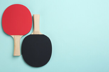 Ping pong rackets on turquoise background, flat lay. Space for text
