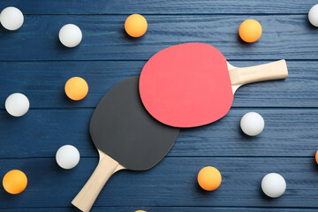 Ping pong rackets and balls on blue wooden table, flat lay