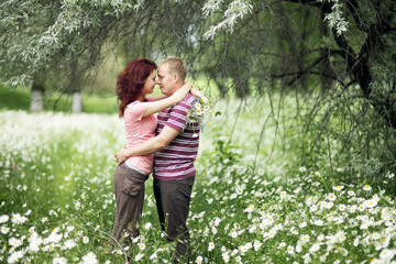 Enamored guy and girl in a green park with white daisies