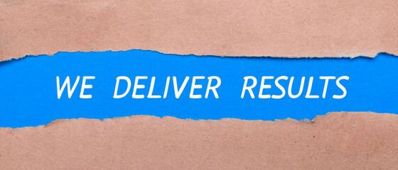 A strip of blue paper with the words WE DELIVER RESULTS between the brown paper. View from above