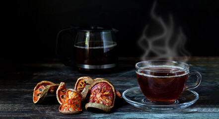 Hot Bael Juice is clear in a clear cup and a dry piece of bael is placed on a wooden floor