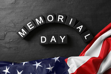 Fototapeta na wymiar Cubes with phrase Memorial Day and American flag on black table, flat lay