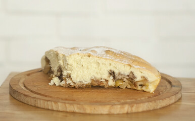 charlotte pie with apples sprinkled with powdered sugar a piece lies on the board