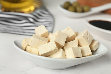 Pieces of delicious tofu on white table, closeup. Soybean curd