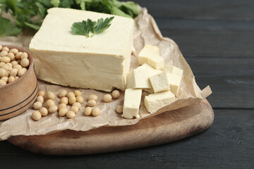 Pieces of delicious tofu with parsley and soy on black wooden table, closeup