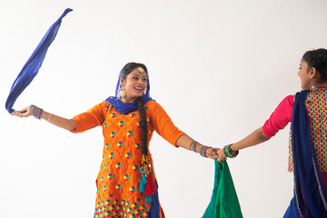 Two Giddha dancers depicting a dance step with colourful cloth in their hands.	