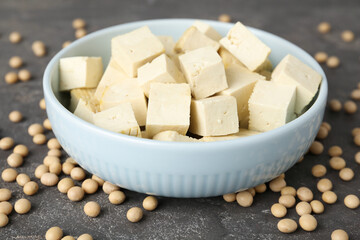 Cut tofu and soya beans on grey table, closeup