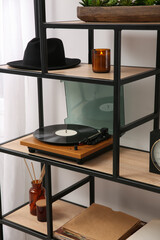 Stylish turntable with vinyl record on shelving unit indoors