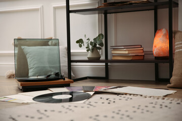 Stylish turntable with vinyl records on floor indoors