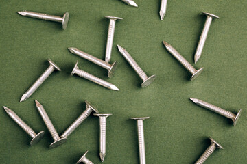 Metal nails close up, lots of nails on a green background.