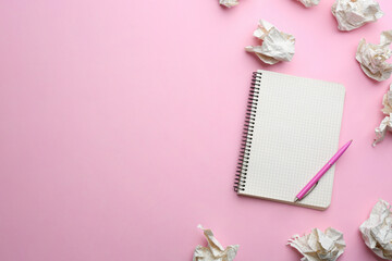 Notebook, pen and crumpled sheets of paper on light pink background, flat lay. Space for text