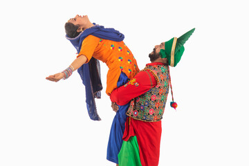 A Bhangra Dancer lifting a Giddha dancer depicting  a dance step.	
