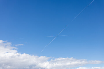 Blue sky with interesting crossing vapour trails - chemtrail
