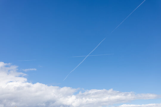 Blue sky with interesting crossing vapour trails - chemtrail