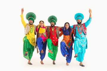 A troupe of Punjabi Folk dancers dressed in costume striking a dance step in unison.	