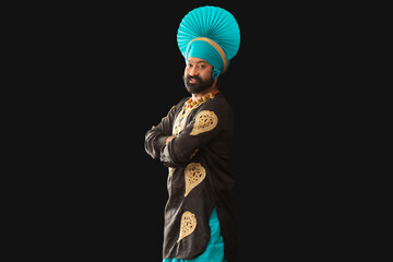 A man in Bhangra Costume smiling with his hands folded.	